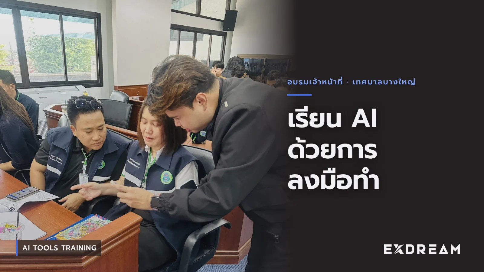 Video poster: a trainer leaning in to look at a phone with two municipal staff in the meeting hall