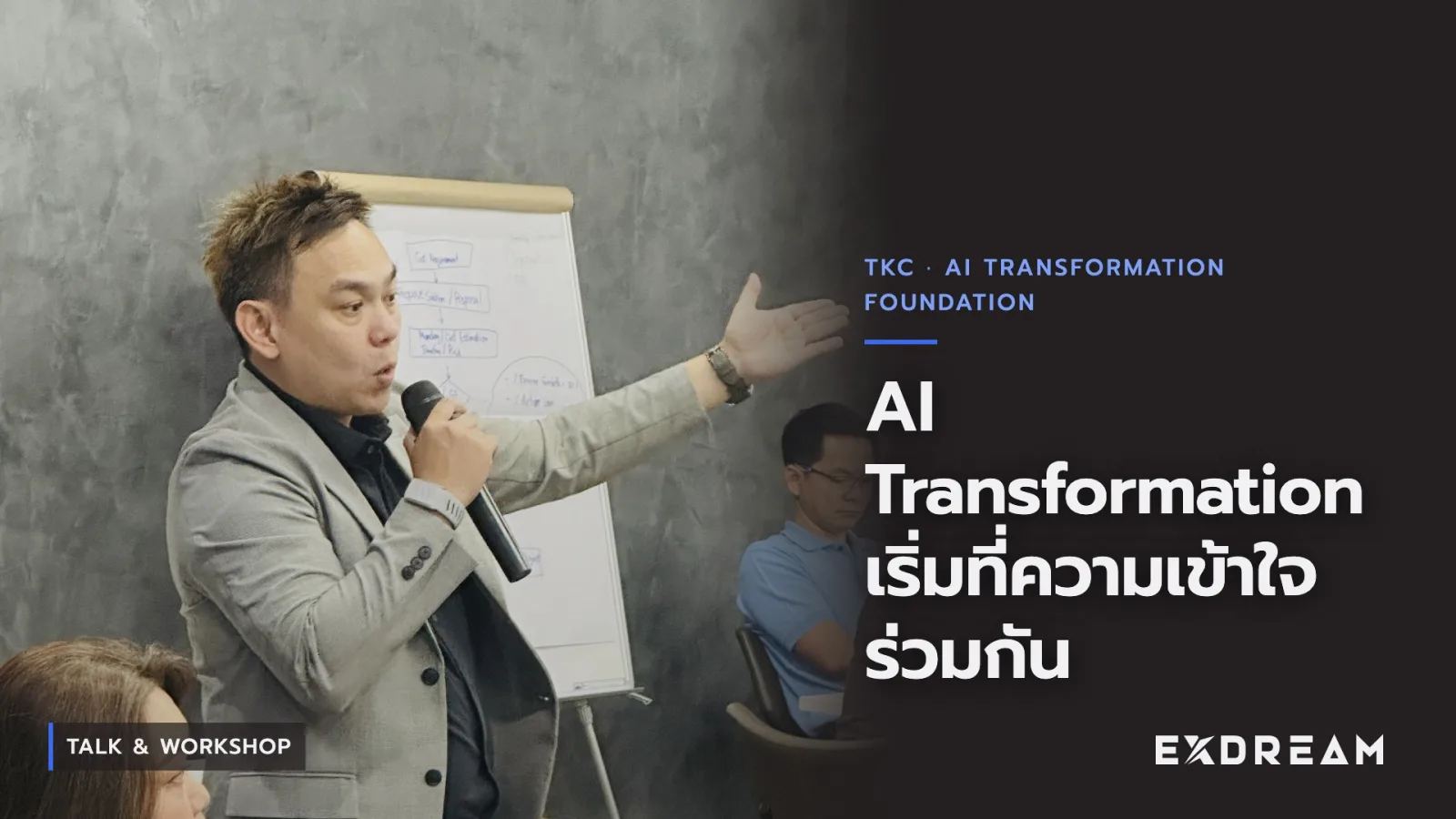 Video poster: the speaker with a microphone gesturing toward a flipchart in the TKC training room